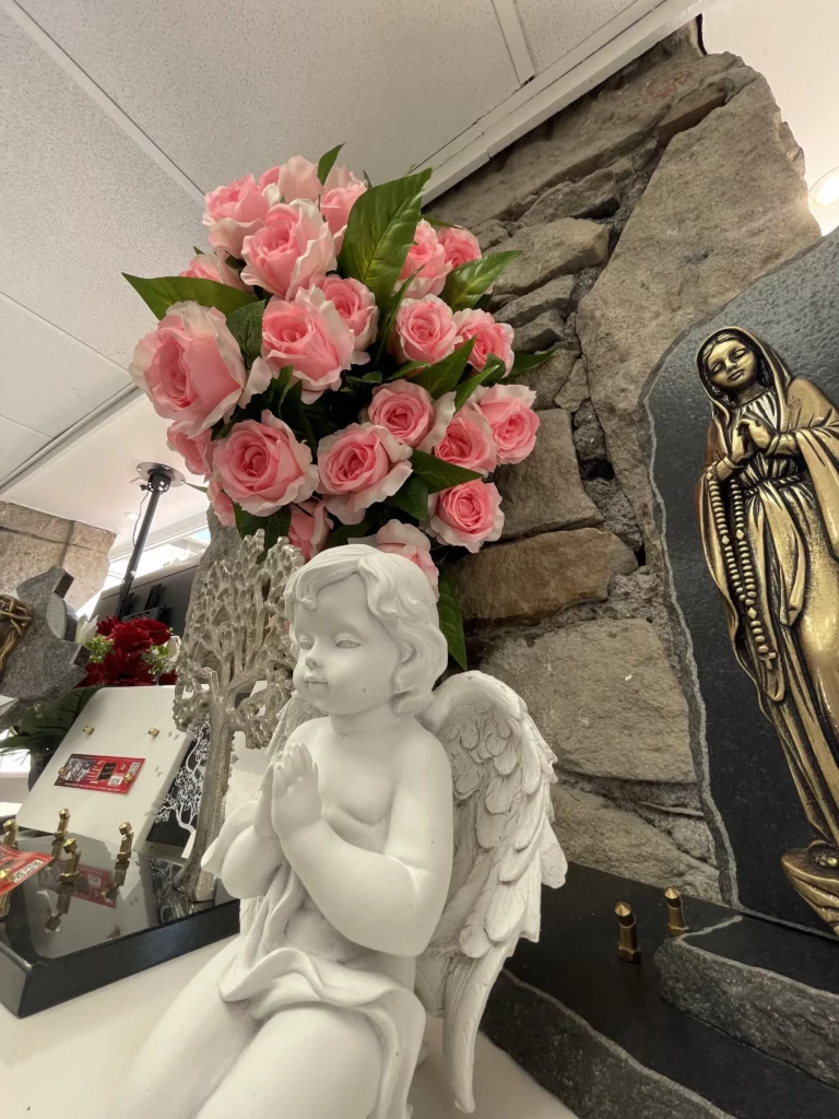 Statue d'ange en prière et bouquet de roses roses dans un salon.