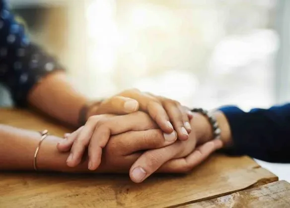 Mains de deux personnes serrées en signe de soutien et de confort.